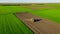 Aerial view of tractor as dragging a sowing machine over agricultural field, farmland