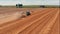 Aerial view of tractor with combine harvester that makes stakes of hay. Harvest of wheat field Agriculture and