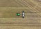 Aerial view of a tractor driving through a freshly tilled farm field, sowing corn seeds in neat rows