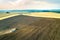 Aerial view of a tractor plowing black agriculture farm field after harvesting in late autumn