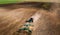 Aerial View. Tractor Plowing Field. Beginning Of Agricultural Spring Season. Cultivator Pulled By A Tractor In