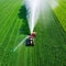 Aerial view tractor spraying the chemicals on the large green