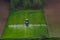 Aerial view of tractor spraying crop in green farm fields with pesticide