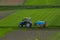 Aerial view of tractor spraying crop in green farm fields with pesticide