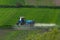 Aerial view of tractor spraying crop in green farm fields with pesticide