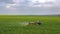 Aerial view of tractor treats agricultural plants on the field