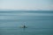 Aerial view of a tranquil seascape with a person paddleboarding in the distance.