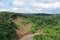 Aerial view of a tropical river that goes in a curve alongside a empty ravine and surrounded by tropical rainforest