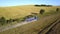 Aerial view of a truck driving on dirt road between plowed fields making lot of dust.