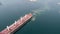 Aerial view of tug boat assisting big cargo ship. Large cargo ship enters the port escorted by tugboats