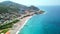 Aerial view of turquoise sea and sand shore. Clip. Concept of summer holidays and tourism, southern town and green hills