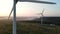 Aerial view of two windmill with rotating blades, working wind turbine among the woodlands at beautiful sunset