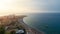 Aerial view of umbrellas, palms on the sandy beach at sunny day. Summer holiday in Greece. Blue sea and the Rhodes city.