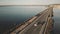 Aerial view of unknown white car driving along the dam at sea in the evening. Orbetello, Italy