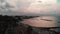 Aerial view of unpopulated tourist and beach area with unoccupied sunbeds and umbrellas in the evening. Drone shot of couple walki