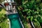 Aerial view of unrecognizable slim young woman in beige bikini relaxing and sunbathe near luxury swimming pool in green tropic in