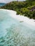 A aerial view of untouched sandy beach with palm trees and lonely tourist boat in blues clear lagoon on Therese Island