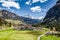 Aerial view of valley with Chalet, green slopes of the mountains of Italy, Trentino, Fontanazzo, huge clouds over a valley, roofs