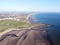 Aerial view of a vast expanse of sandy beach and the crystal blue waters of the ocean beyond.