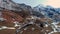 Aerial view of a very slow backward movement in a valley with snow, rural houses and a road