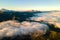 Aerial view of vibrant sunrise over white dense fog with distant dark Carpathian mountains on horizon