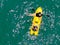 Aerial view view of strong young active men capsizing with their kayak on the clear blue ocean.