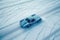 Aerial View of Vintage Blue Racing Car with Intricate White Line Patterns on Snowy Road