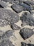 Aerial view of volcanic black rocks in the sand. Porous lava stones of different sizes in the sand. Geology background. Volcanic