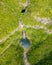 Aerial view of a waterfall cascading down the green mountains on a sunny day