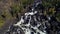 Aerial view of waterfall, flying over autumn forest, waterfall with big stones