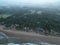 Aerial view of the wavy seacoast and dense foggy forest with several buildings under the foggy sky