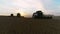 Aerial view of wheat three silhouette of harvests. Drone shot flying over three combine harvesters working on wheat