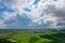 Aerial view of white clouds and green lush farmland fields