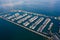 Aerial view of a white motor yacht. Yacht enters the bay in the parking lot. Many different yachts, catamarans moored to piers.