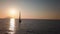 Aerial view on white sailboat anchored in Mediterranean sea against Lipari Island and rock. Sun reflecting in water