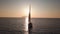 Aerial view on white sailboat anchored in Mediterranean sea against Lipari Island. Sun reflecting in water surface