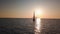 Aerial view on white sailboat floating in Mediterranean sea against Lipari Island. Sun reflecting in water surface