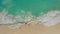 Aerial view of white sand beach with tourists and azure blue water, ocean waves