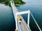 Aerial view of white suspension bridge with car crossing over blue lake in Finland