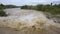 Aerial view of wide dirty river with muddy yellow water flowing through a city in flooding period during heavy rains in spring.