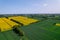 Aerial view Wind turbine on grassy yellow farm canola field against cloudy blue sky in rural area. Offshore windmill