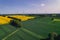 Aerial view Wind turbine on grassy yellow farm canola field against cloudy blue sky in rural area. Offshore windmill