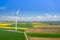 Aerial view of wind turbine. Rapeseed blooming. Windmills and yellow fields from above. Agricultural fields on a summer day.