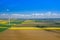 Aerial view of wind turbine. Rapeseed blooming. Windmills and yellow fields from above. Agricultural fields on a summer day.