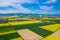 Aerial view of wind turbine. Rapeseed blooming. Windmills and yellow fields from above. Agricultural fields on a summer day.
