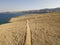 Aerial view of a winding road that runs along the Croatian coasts, dirt road, island of Pag near Rucica beach in Metajna. Croatia