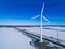 Aerial view of windmills with blue frozen river in snow winter Finland. Wind turbines for electric power