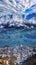 Aerial view of winter city and lake with reflection of sunny Alp mountains under dramatic sky