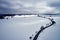 Aerial view of a winter curved road covered with snow. A snowy plateau with single trees captured from above with a