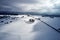 Aerial view of a winter curved road covered with snow. A snowy plateau with single trees captured from above with a